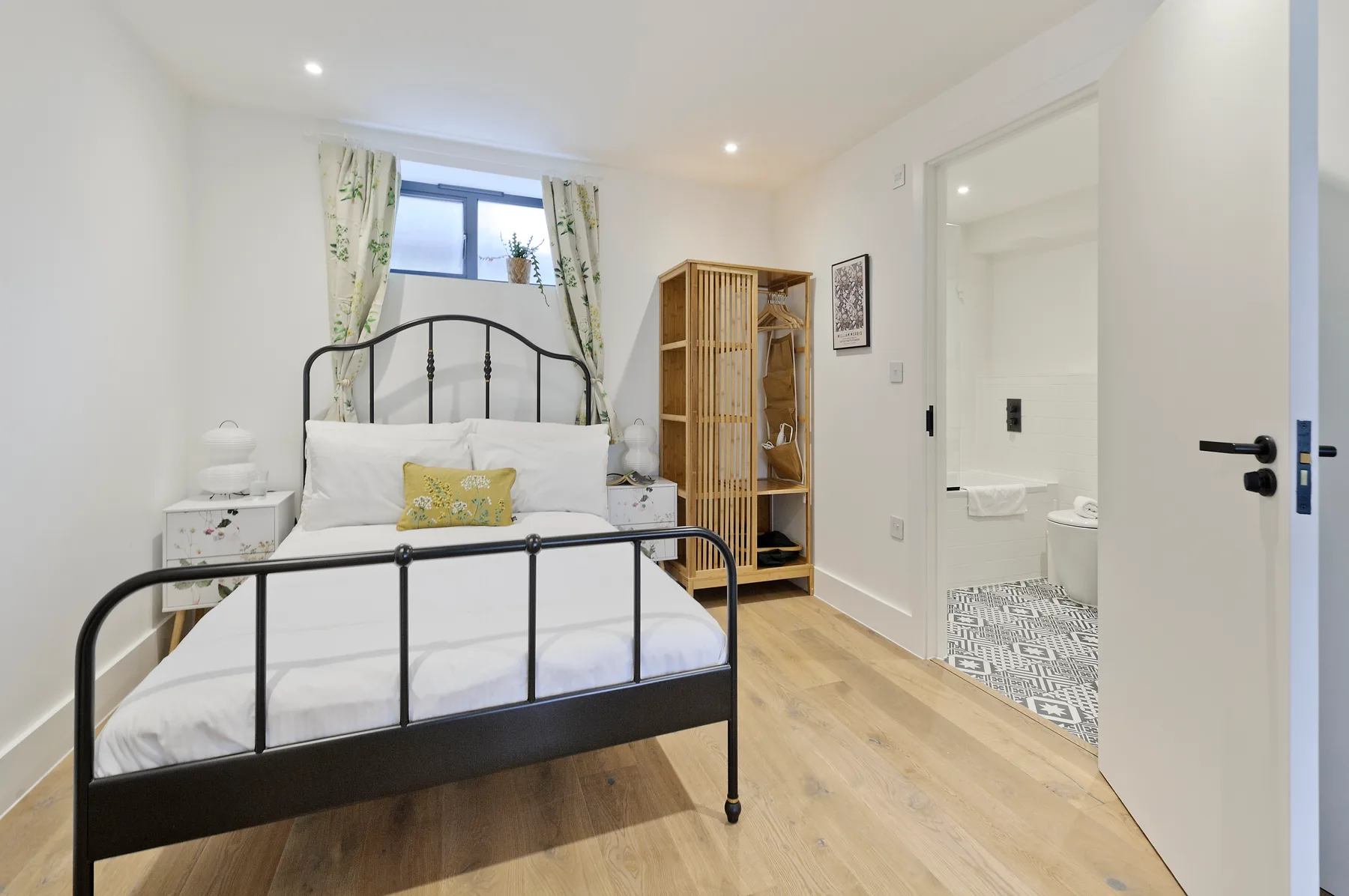 A bedroom with a metal bed, a window, and a wooden floor.