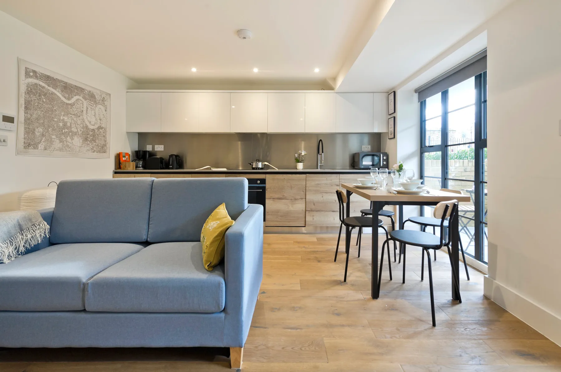 A modern open-plan living and dining area with a kitchen behind the seating.