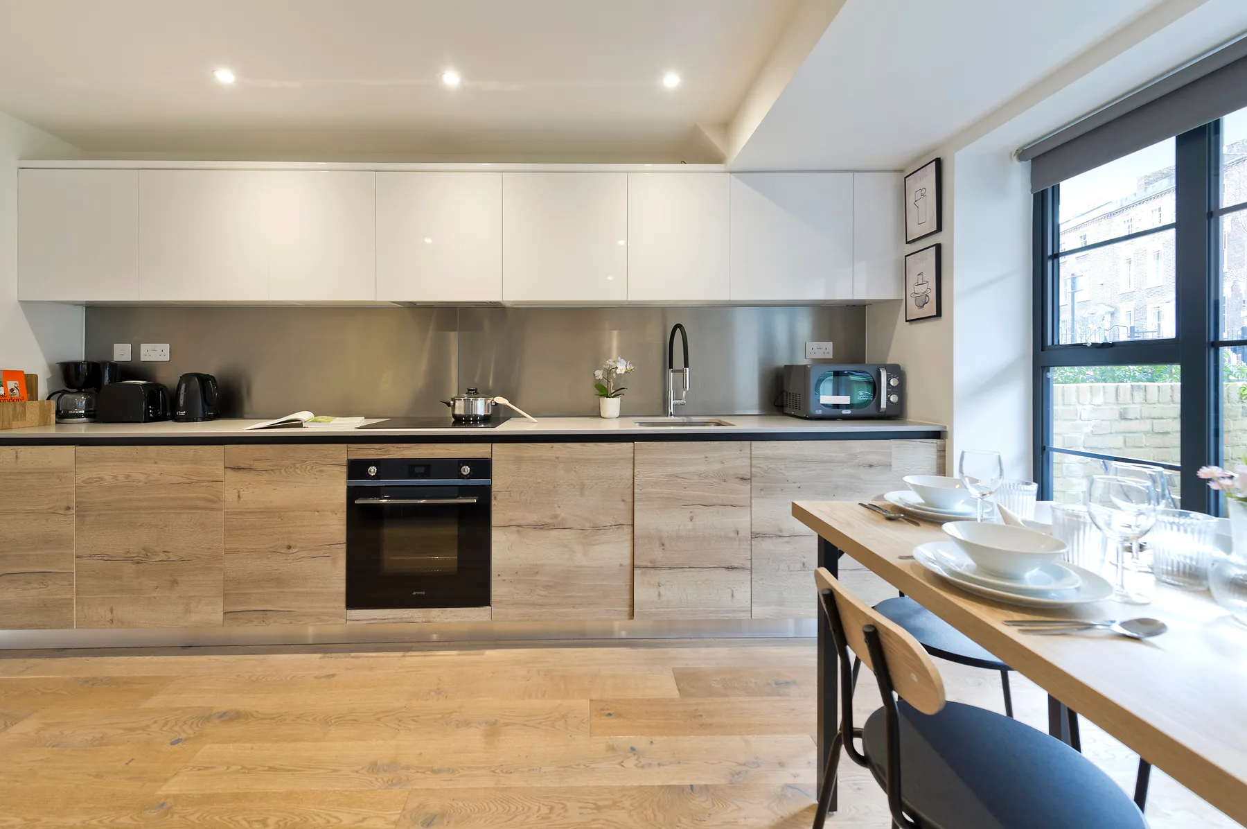 A bright kitchen and dining area with wood cabinetry and a table beside large windows.