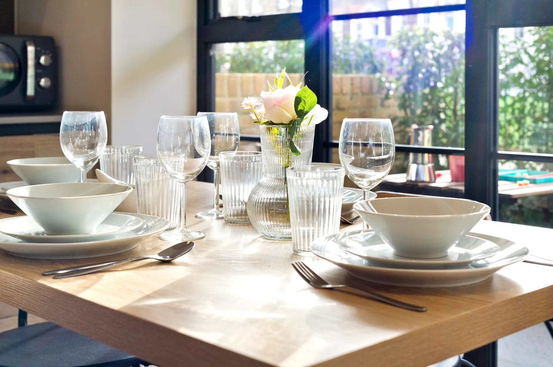 A dining table is set with dishes, glasses, and a small flower arrangement.