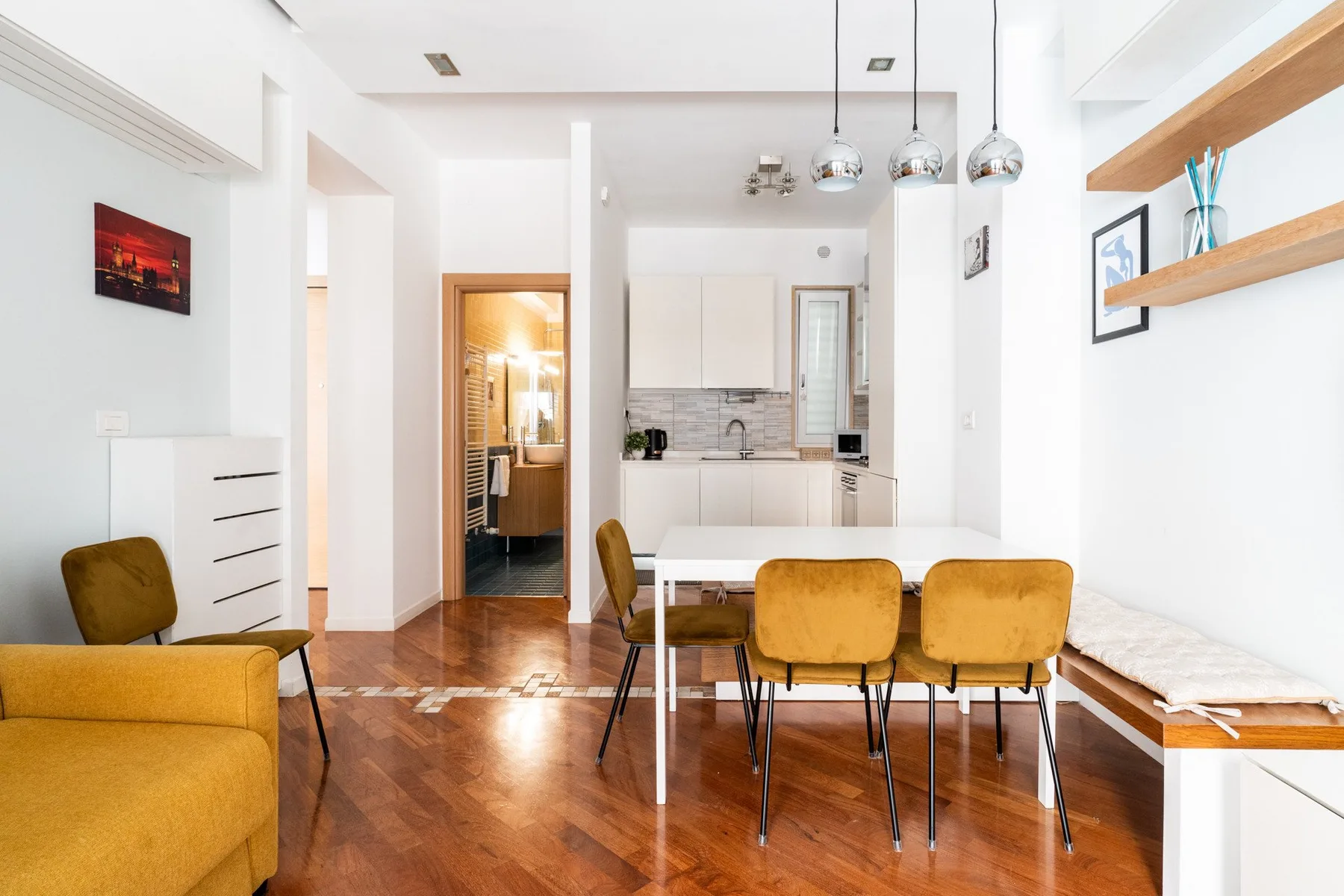 Un luminoso comedor integrado con cocina, mesa de madera y asientos.