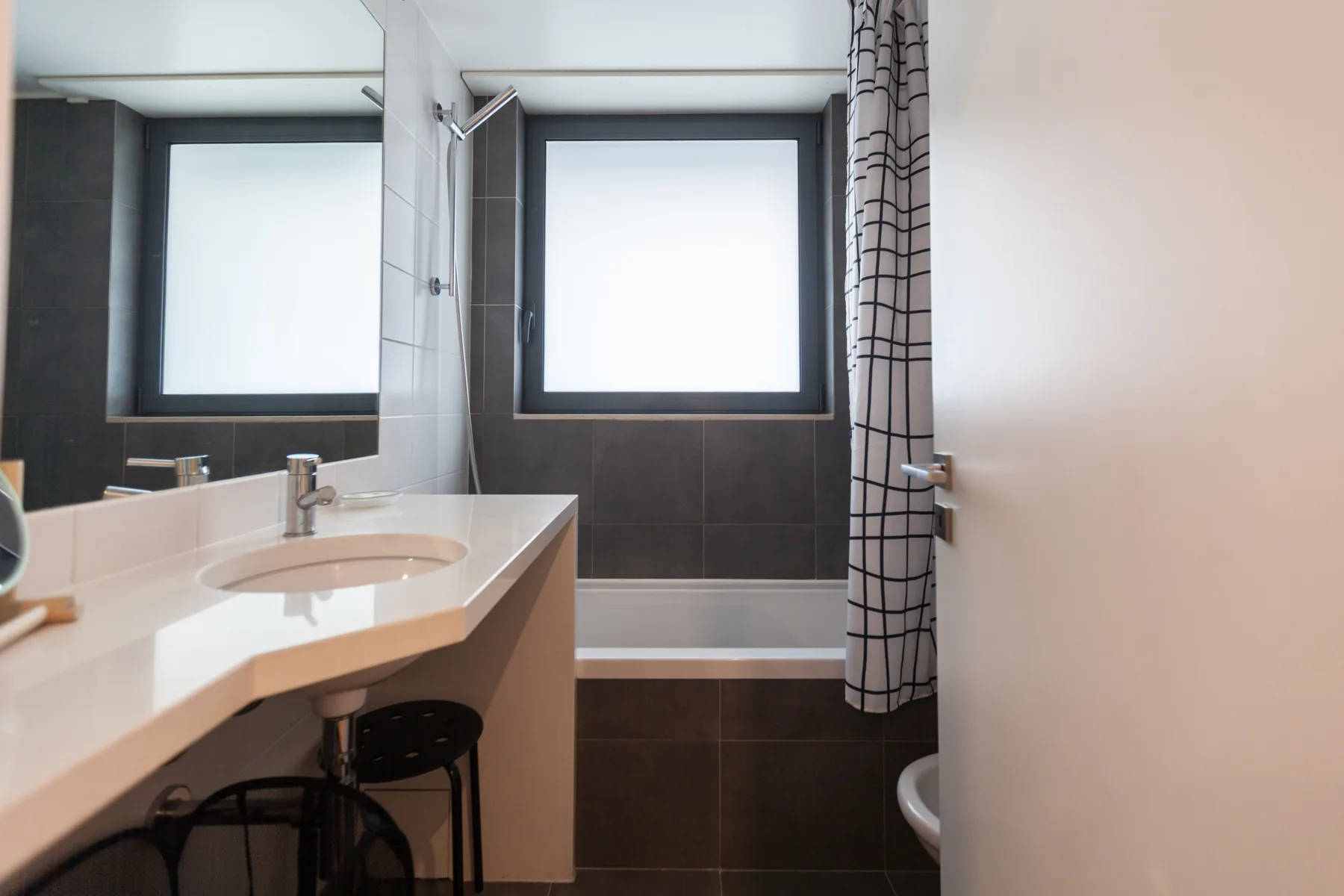 Un baño con lavabo y bañera bajo una ventana.
