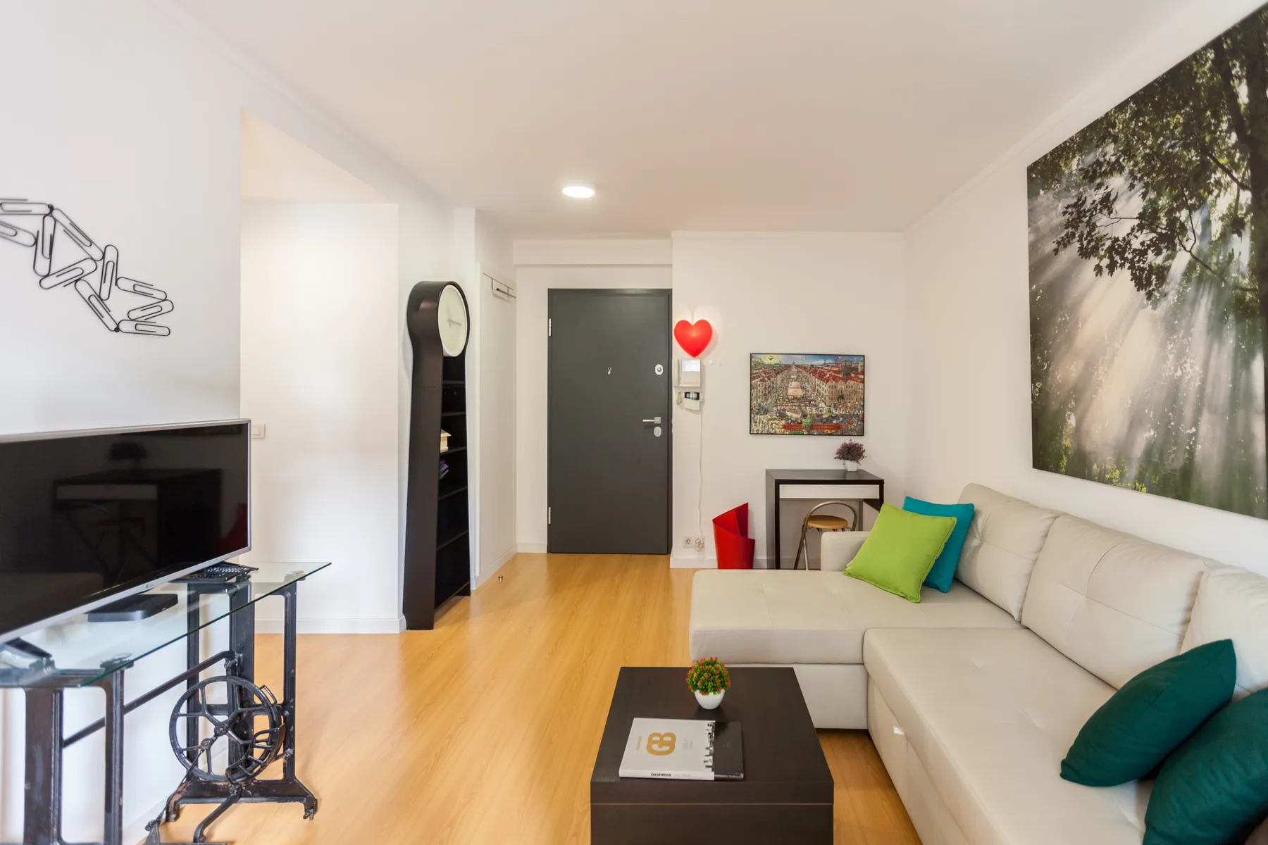 Una sala de estar con zona de asientos, televisor y mesa de centro.