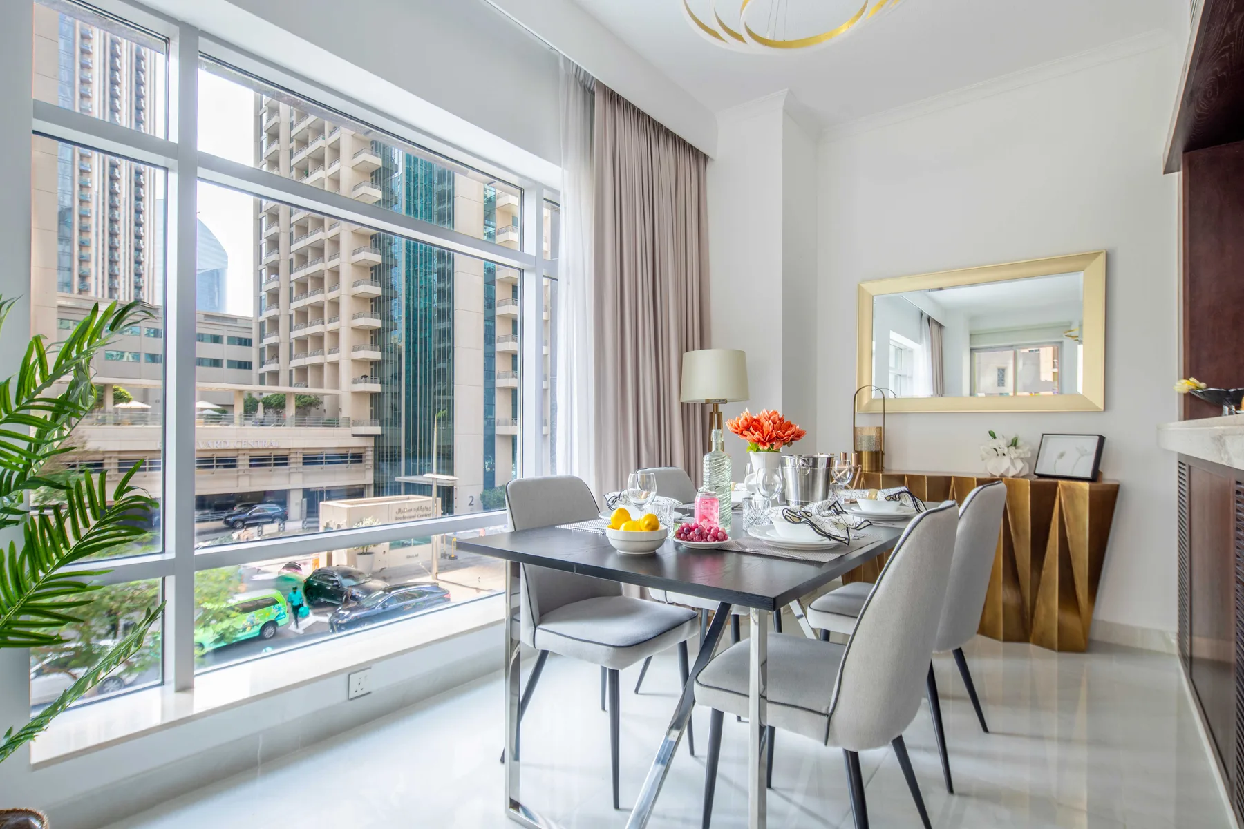 Un comedor luminoso con una mesa junto a grandes ventanas con vistas a edificios de la ciudad.