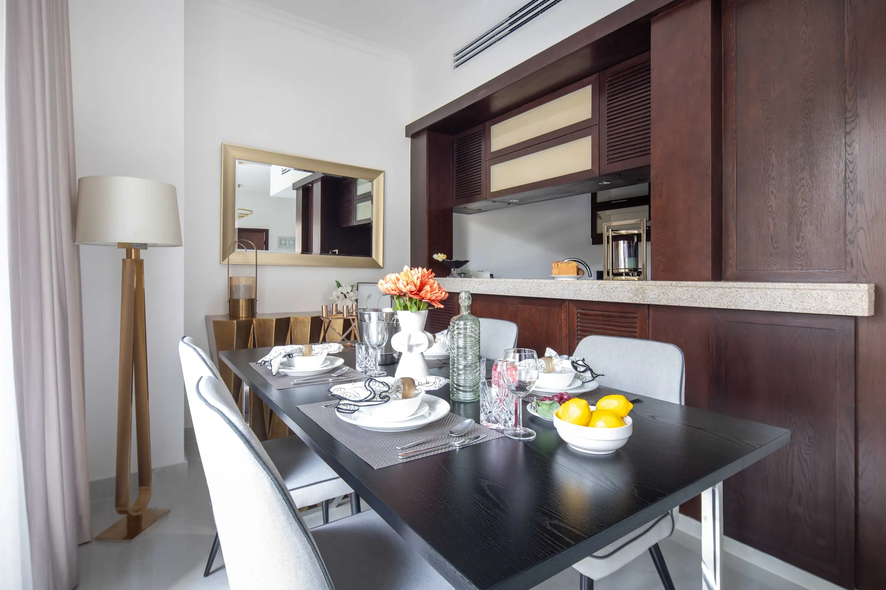 Un comedor con la mesa puesta y gabinetes de madera oscura junto a la pared.