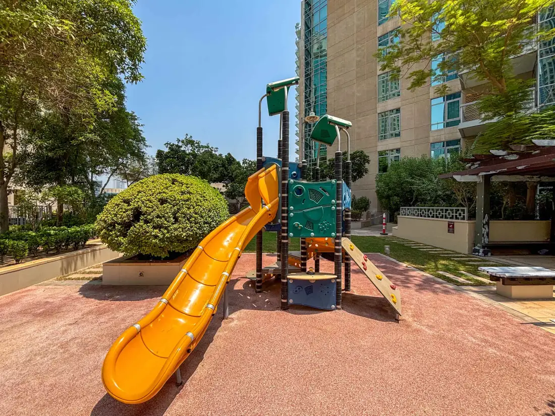 Un parque infantil con un tobogán naranja y una estructura para trepar.