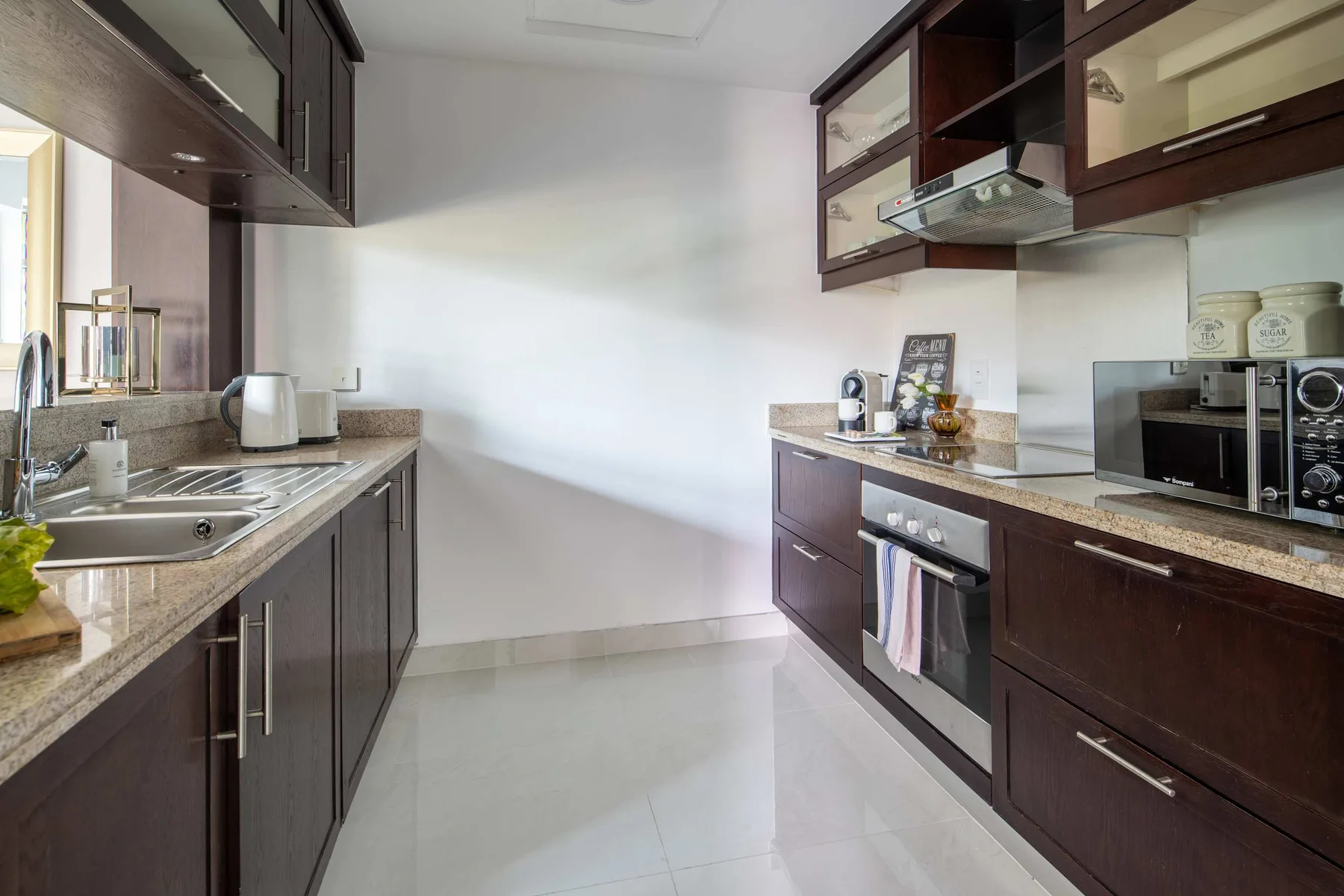 Una cocina moderna con gabinetes oscuros, encimeras y electrodomésticos de acero inoxidable.