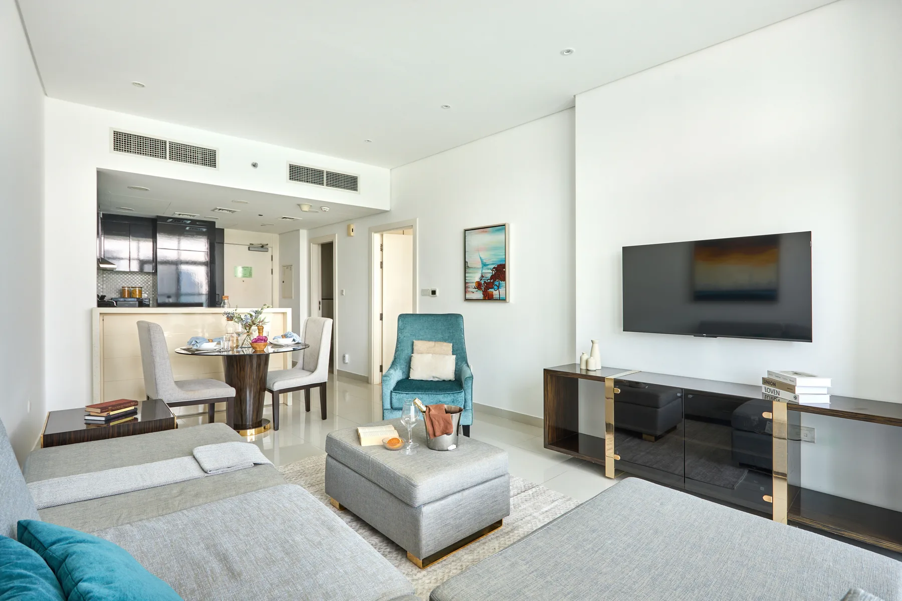 Una sala luminosa con televisor, asientos y un comedor.