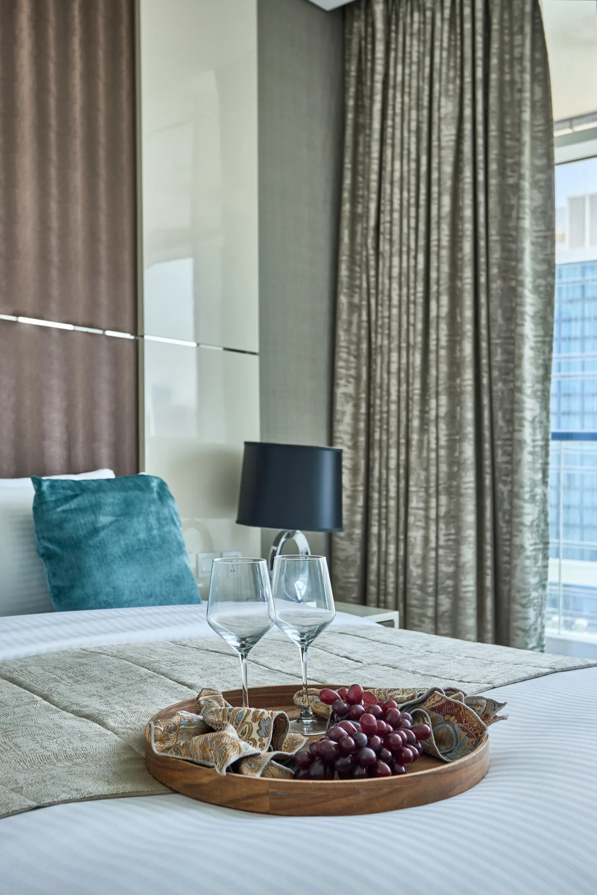 Un dormitorio con una cama, una bandeja de fruta y cortinas largas.