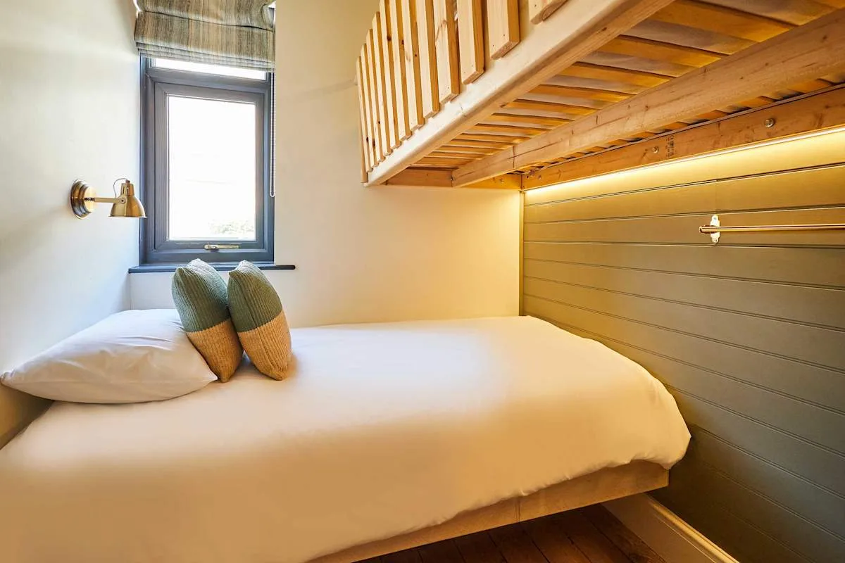 Un dormitorio compacto con una cama debajo de un altillo de madera.