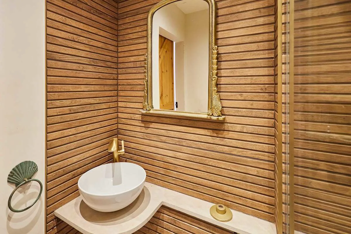 Un tocador de baño con lavabo blanco sobre encimera y espejo enmarcado.