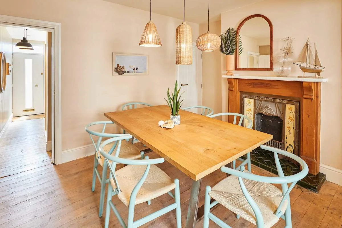 Comedor con mesa de madera y asientos azul claro junto a una chimenea.