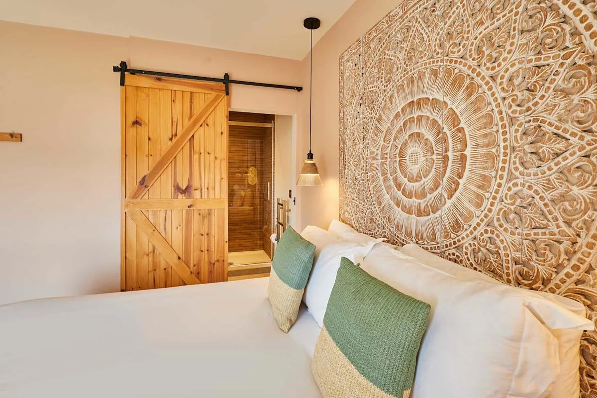Un dormitorio con una cama, cojines verdes y un panel tallado en la pared.