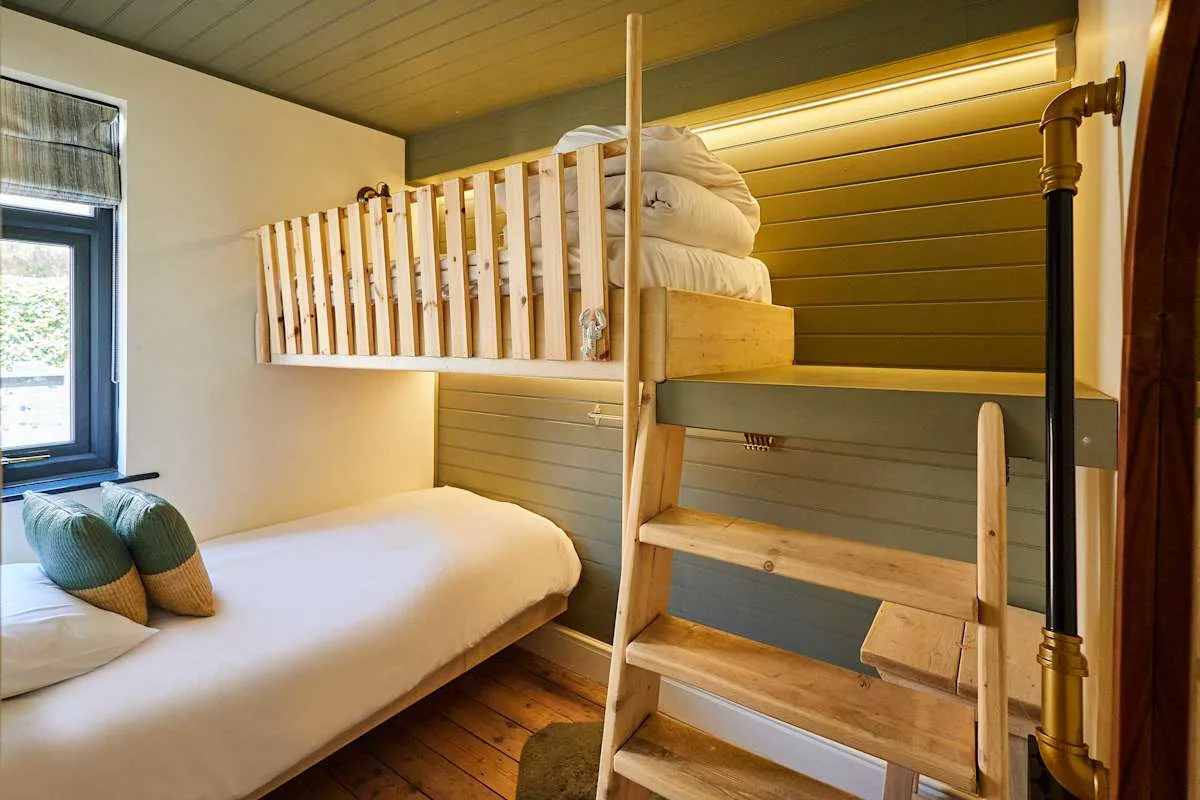 Un dormitorio con una litera elevada sobre una cama inferior y una ventana.