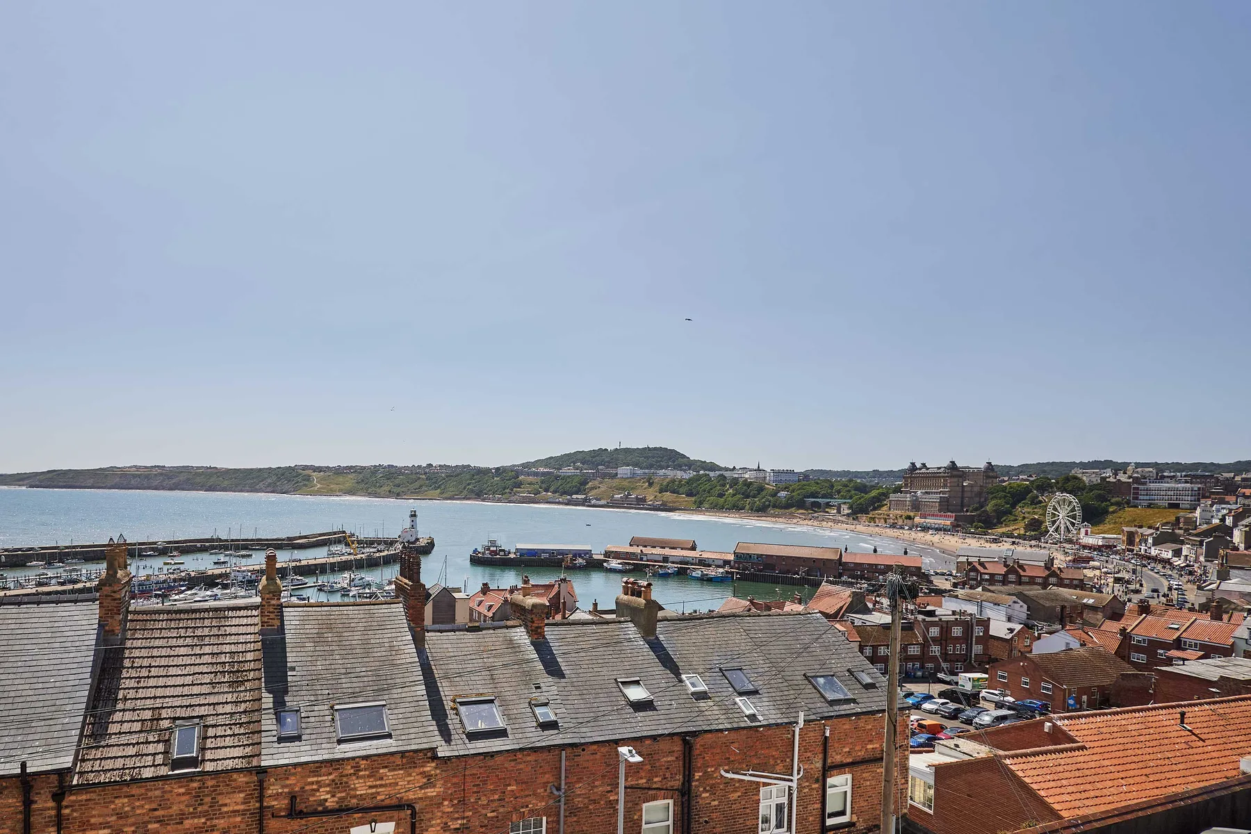 A coastal town and bay are visible beyond nearby rooftops.