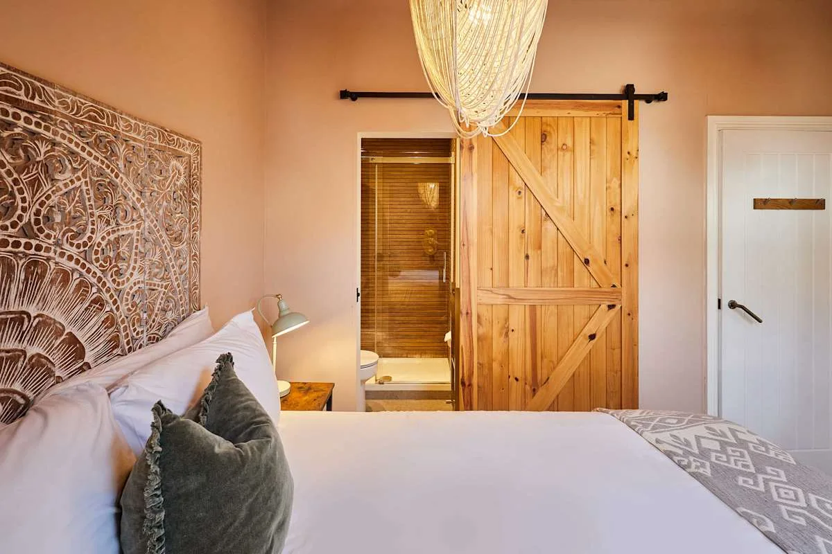 Un dormitorio con una cama, un tapiz estampado y una puerta corredera de madera.