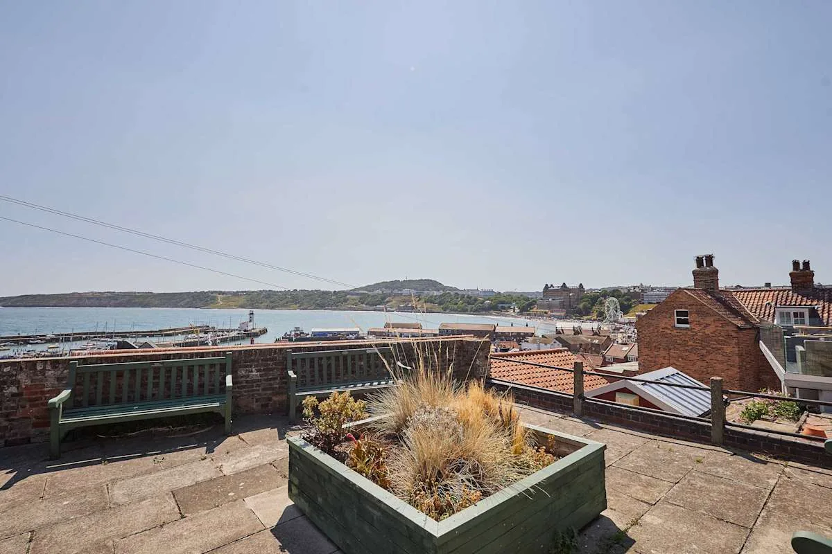 Una terraza en la azotea ofrece vistas al agua, con una jardinera de hierbas ornamentales en primer plano.