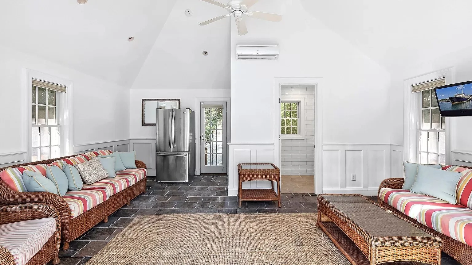 A bright living room with woven seating and a ceiling fan.