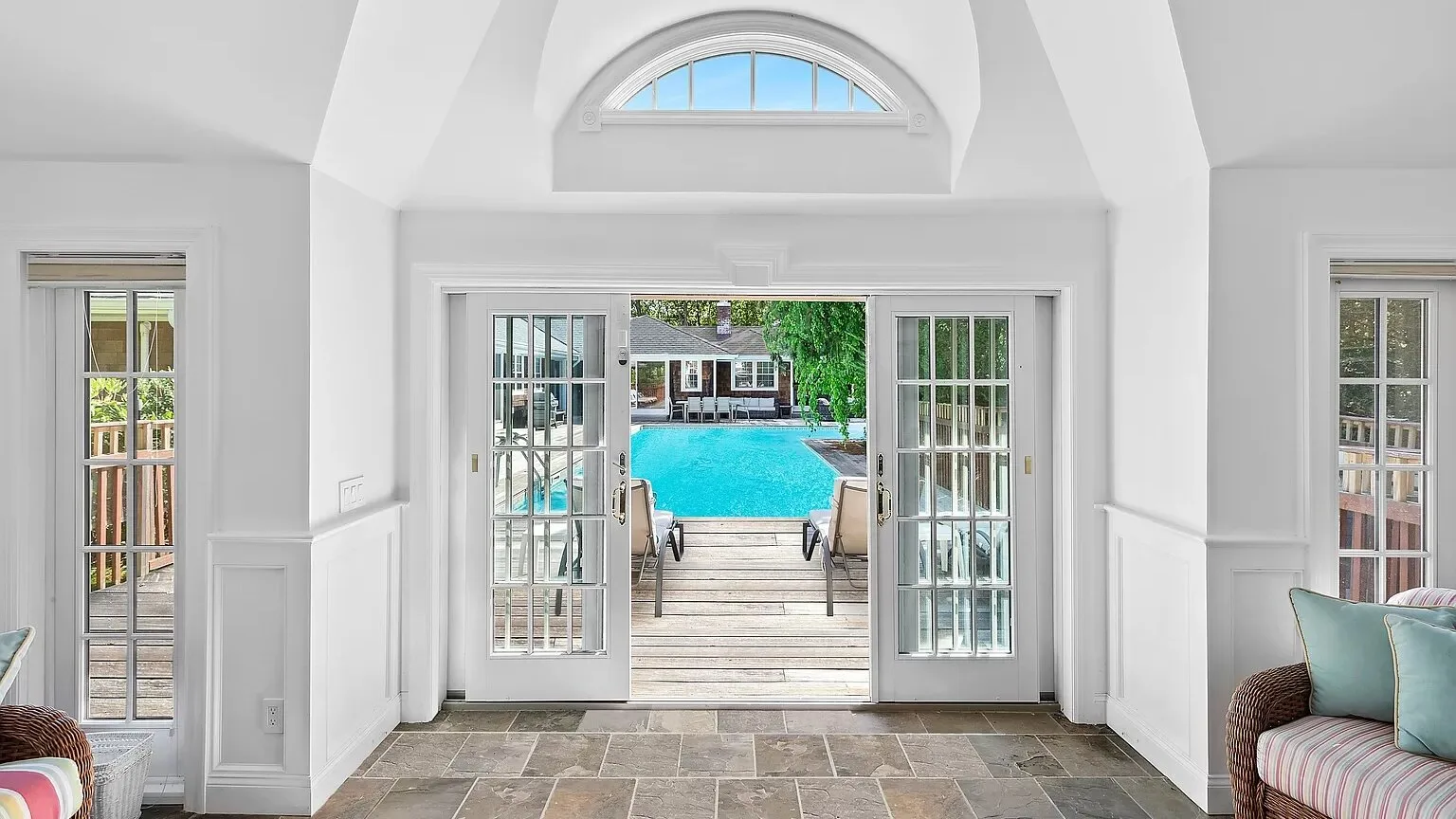 A bright enclosed patio opens through glass doors to a swimming pool.
