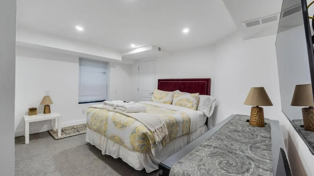 A bright bedroom with a bed dressed in patterned bedding.