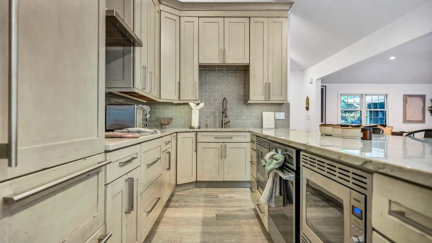A bright kitchen with pale cabinetry, a tiled backsplash, and a central island.