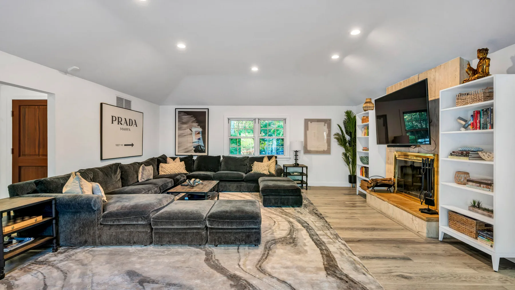 A living room with sectional seating, a large rug, and a television.