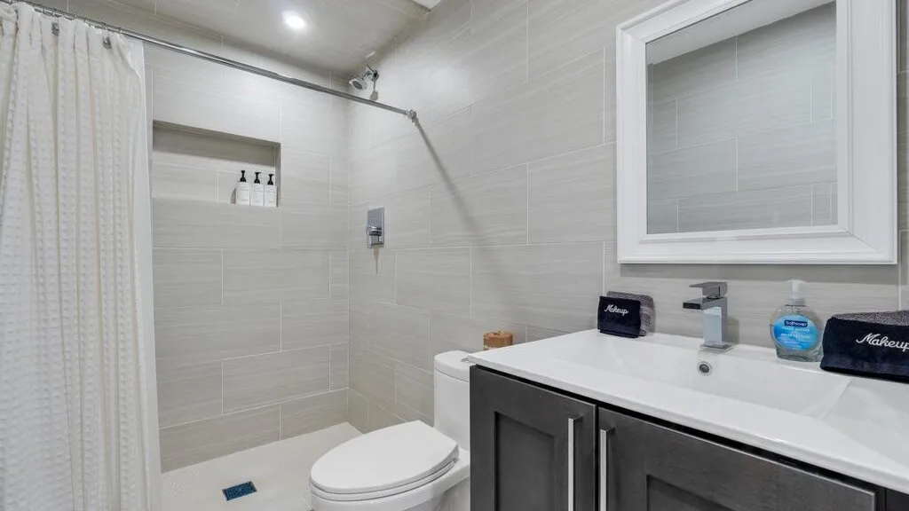 A bright tiled bathroom with a shower and a white vanity.