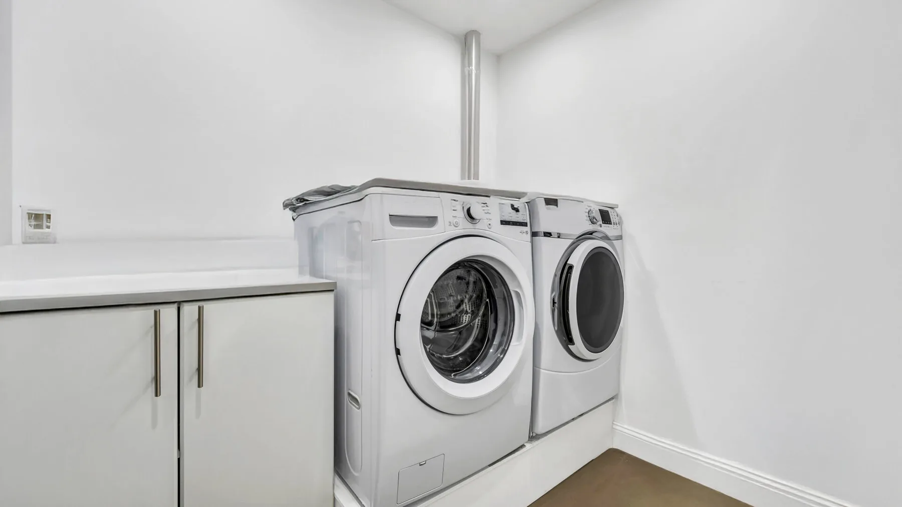 A laundry room with a front-loading washer and dryer beside a counter.