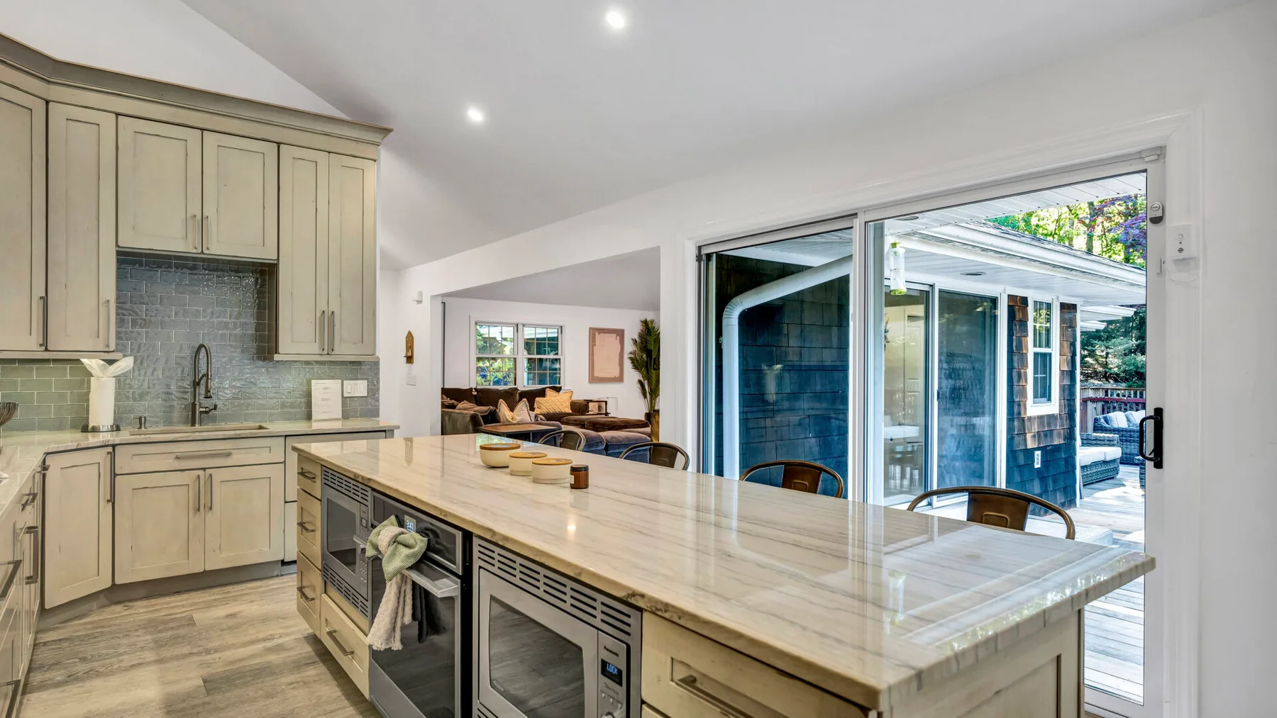 A kitchen with light cabinetry and a wide island opens onto a patio.