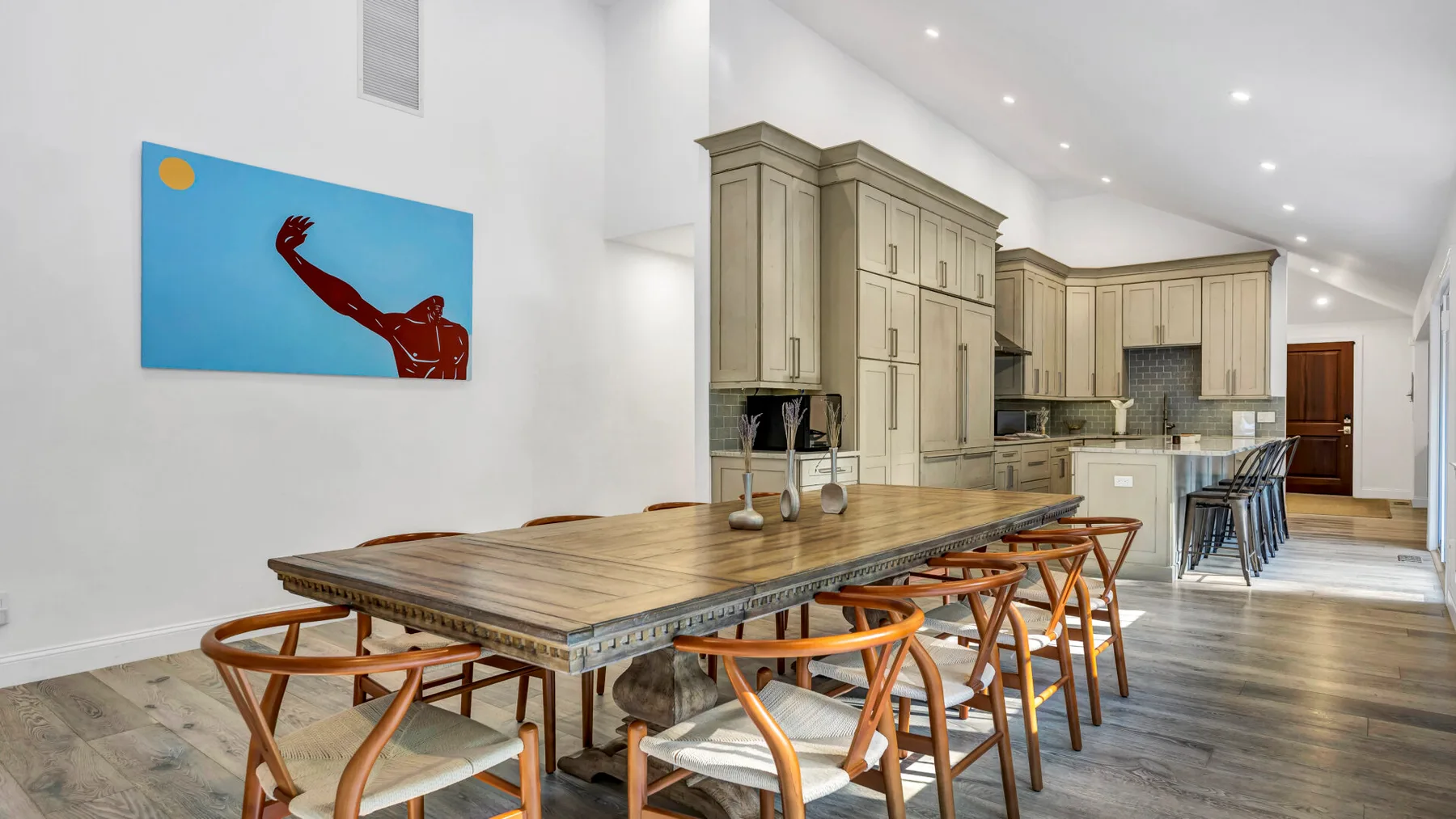 A spacious kitchen and dining area features a long wooden table and built-in cabinets.