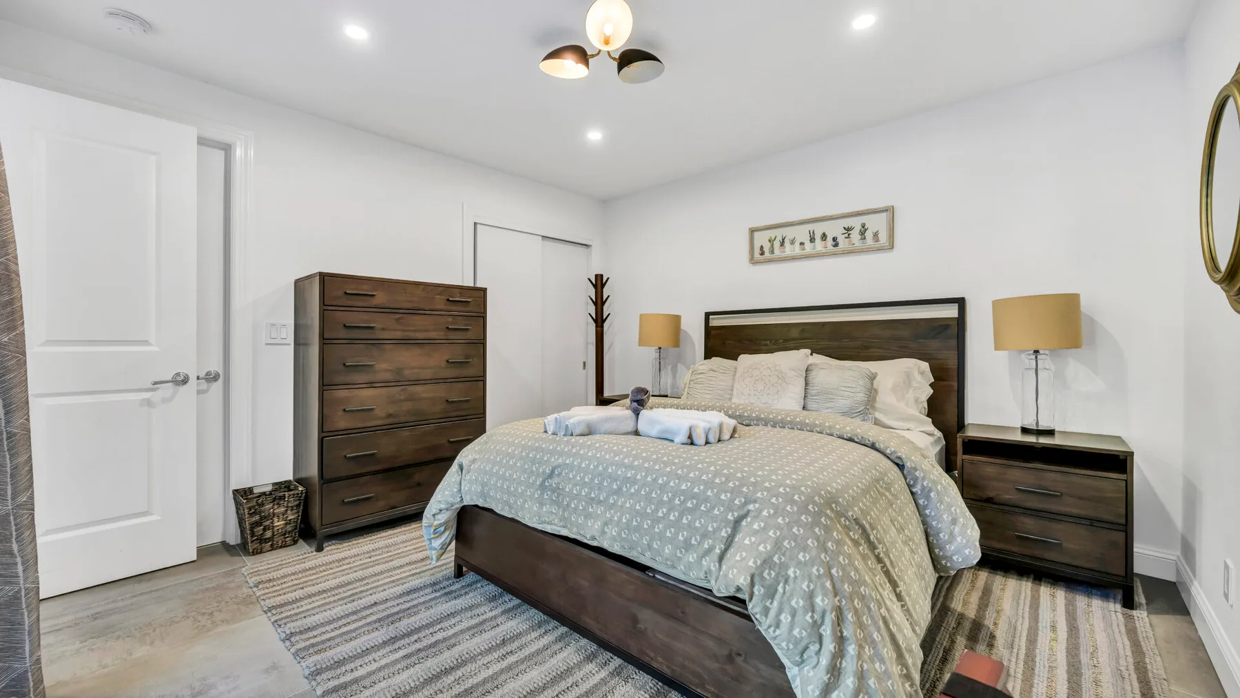 A bedroom with a bed, matching bedside tables, and a striped rug.