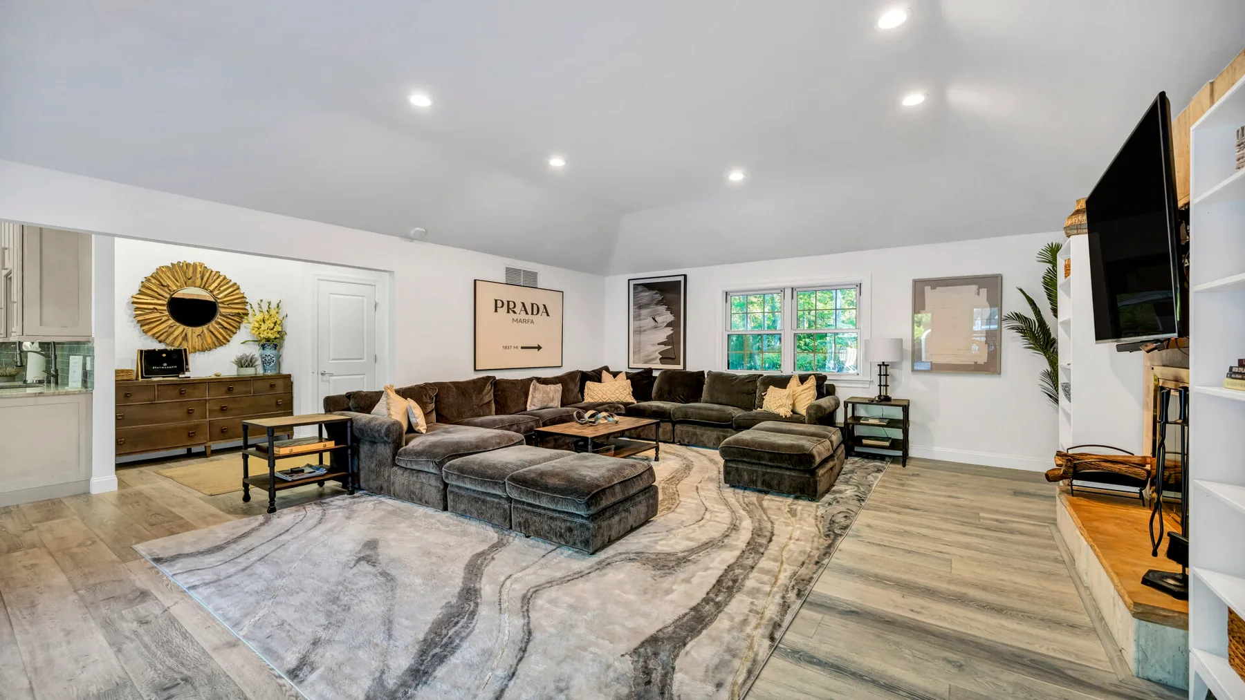A spacious living room with sectional seating, a large rug, and a wall-mounted television.