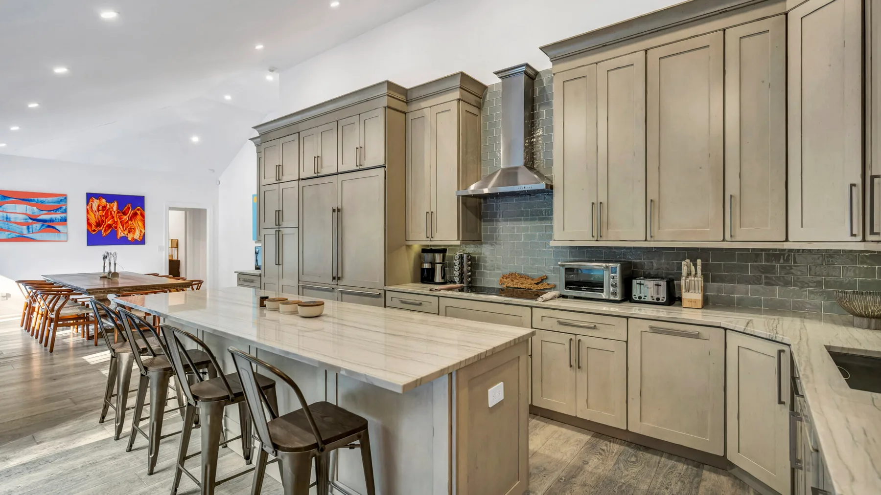 A bright kitchen with a long island, bar seating, and light-colored cabinets.