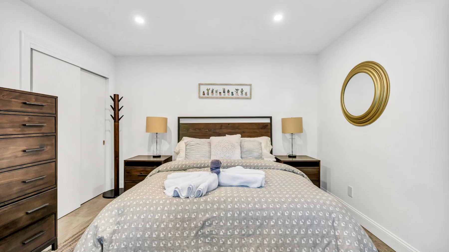 A bright bedroom with a neatly made bed and matching bedside tables.