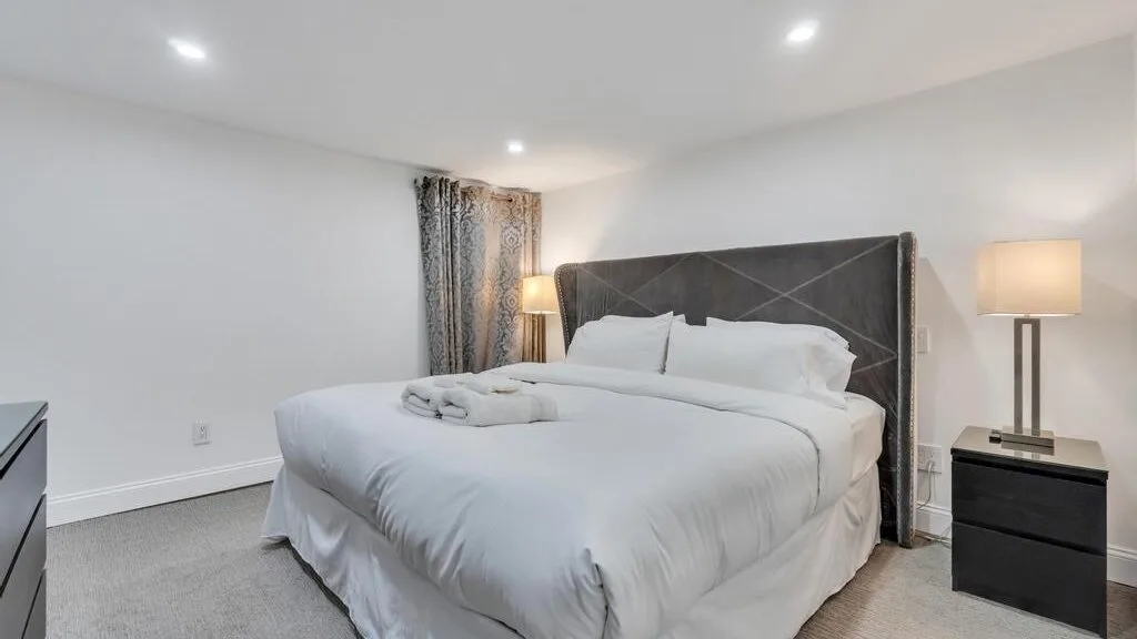 A bedroom with a neatly made bed and bedside tables.