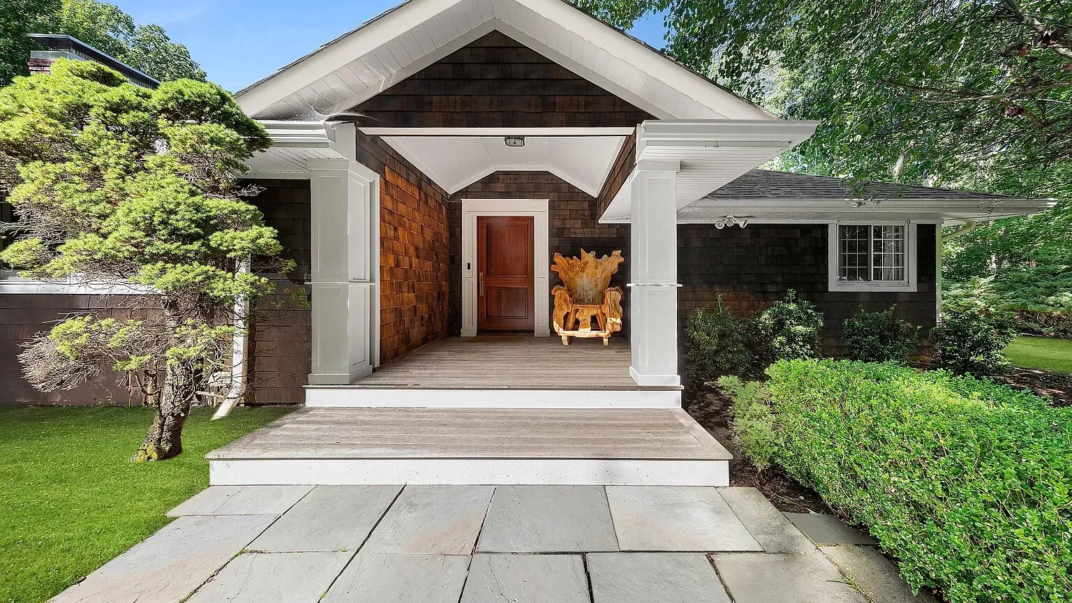 A house entrance with a covered porch, front door, and paved walkway.