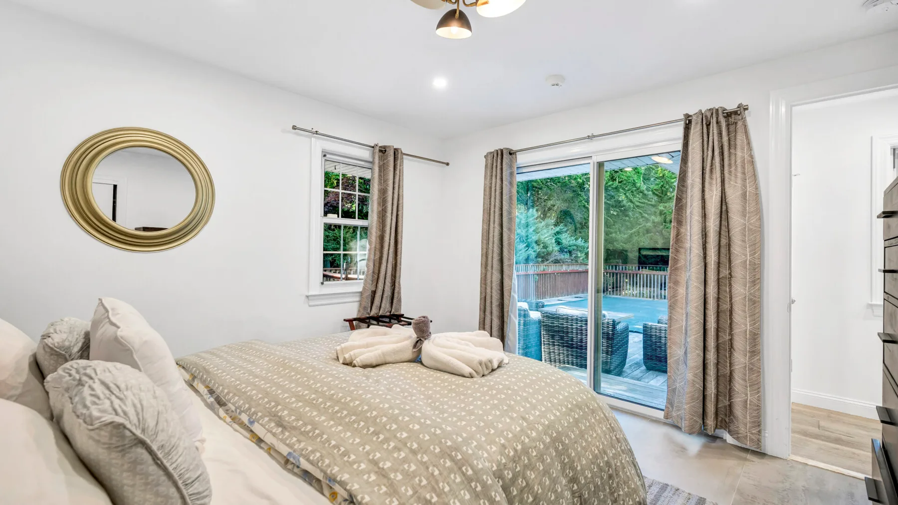 A bedroom with a bed beside a sliding glass door and curtained windows.