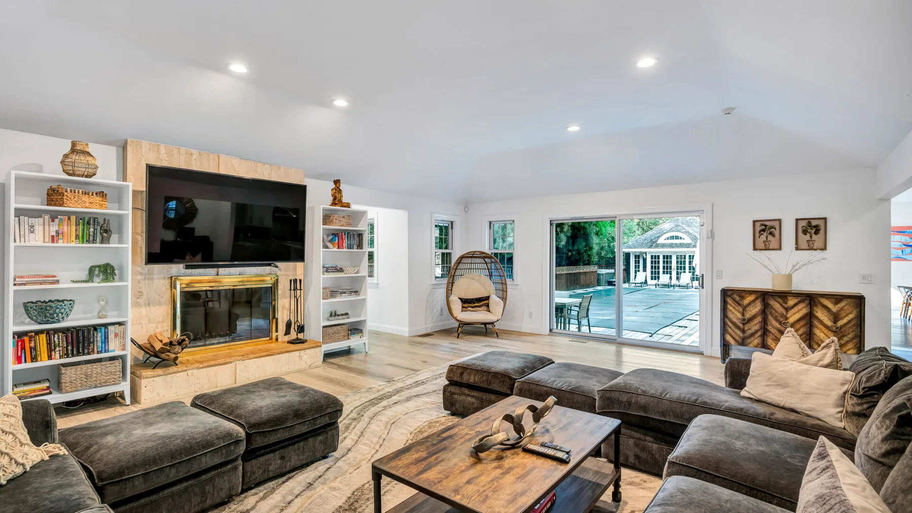 A bright living room with sectional seating, a fireplace, and sliding glass doors.