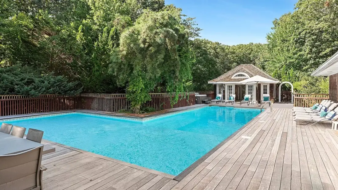 A swimming pool beside a wooden deck, with a small pavilion at the far end.