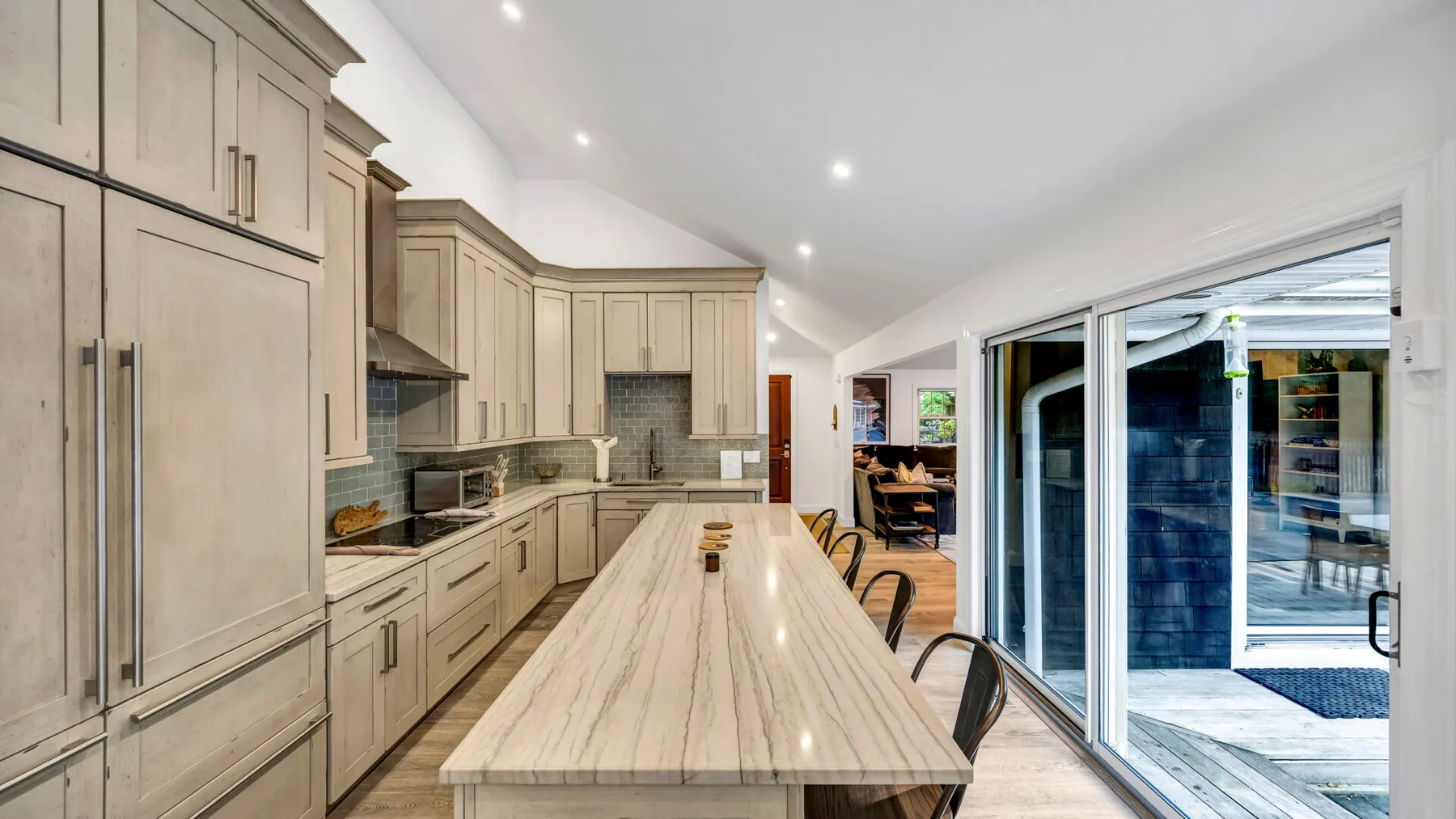 A bright kitchen with a long island and sliding glass doors.