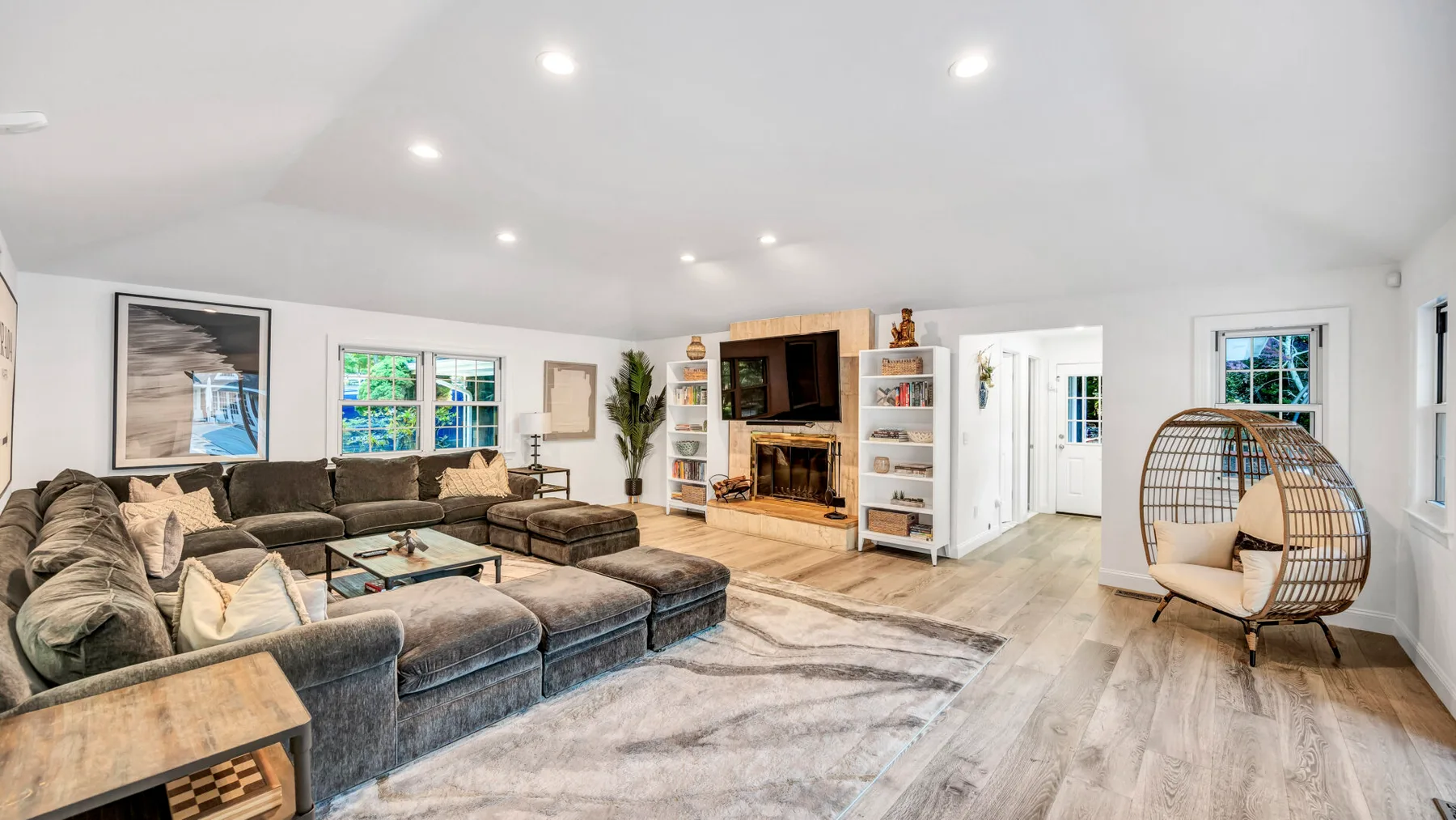 A spacious living room with sectional seating, a fireplace, and large windows.