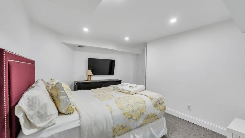 A bedroom with a bed, patterned bedding, and a television on a low stand.