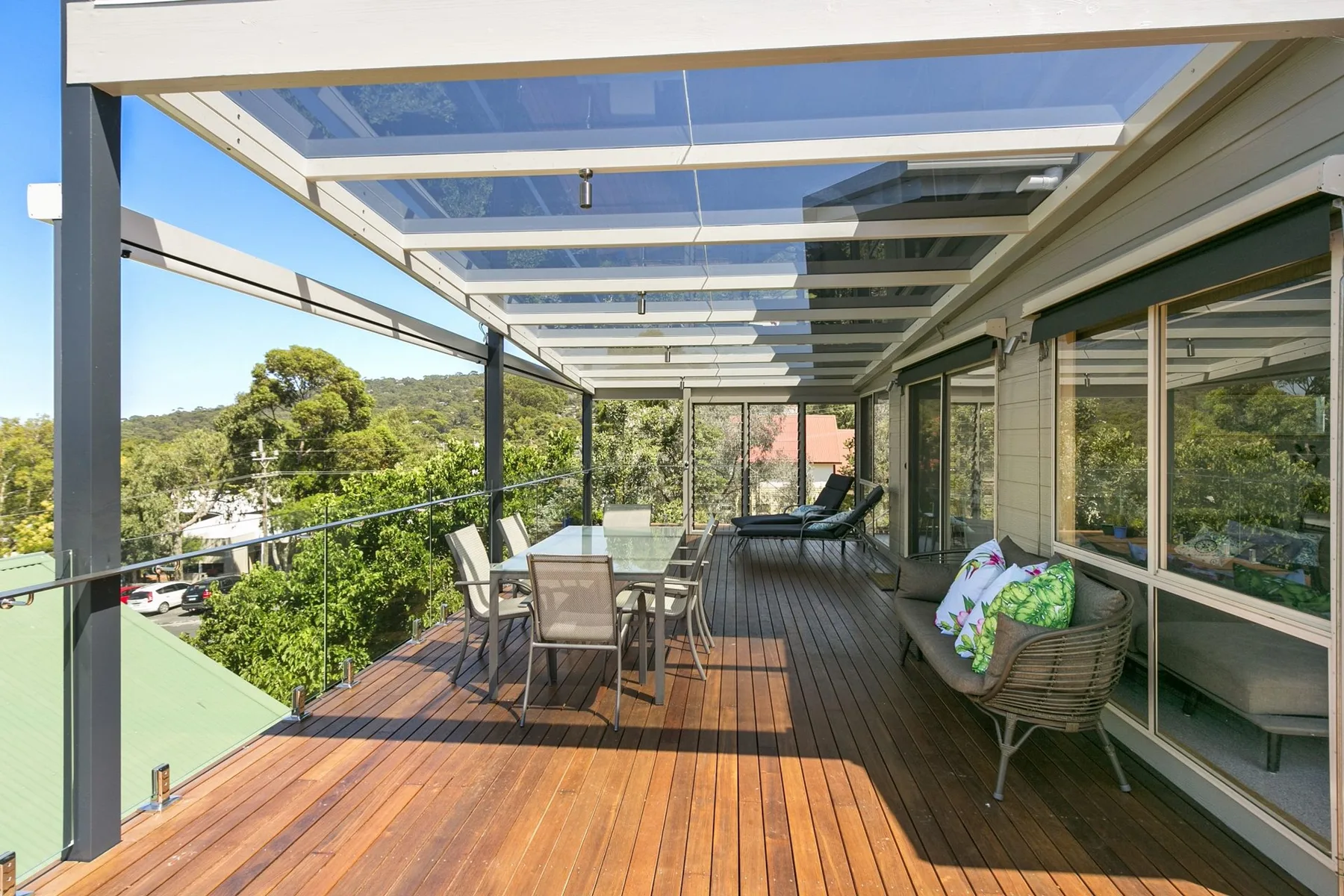 A covered outdoor deck with seating and glass doors overlooking greenery.