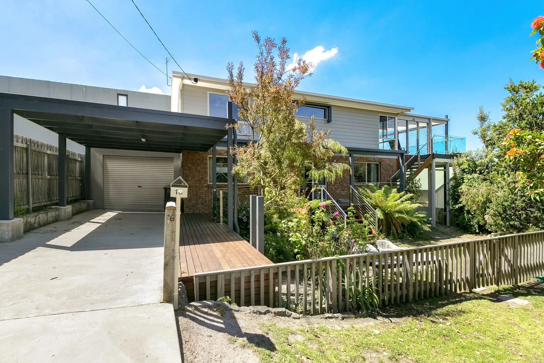 A modern two-story house with a covered driveway and landscaped front garden.