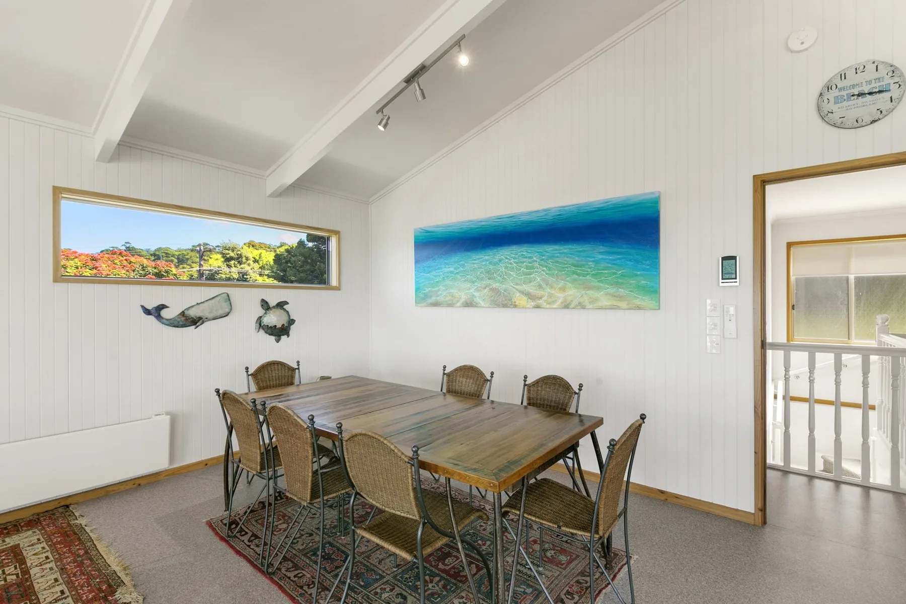 Dining area with a long table and a large ocean picture on the wall.