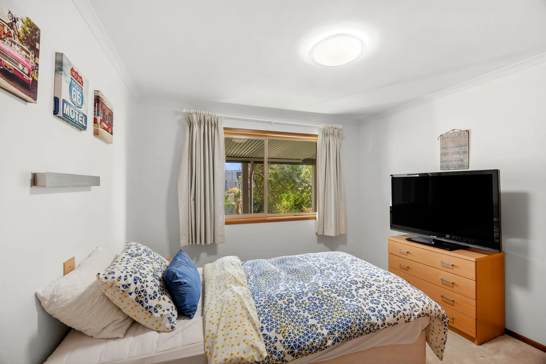 A bedroom with patterned bedding and a television on a dresser.