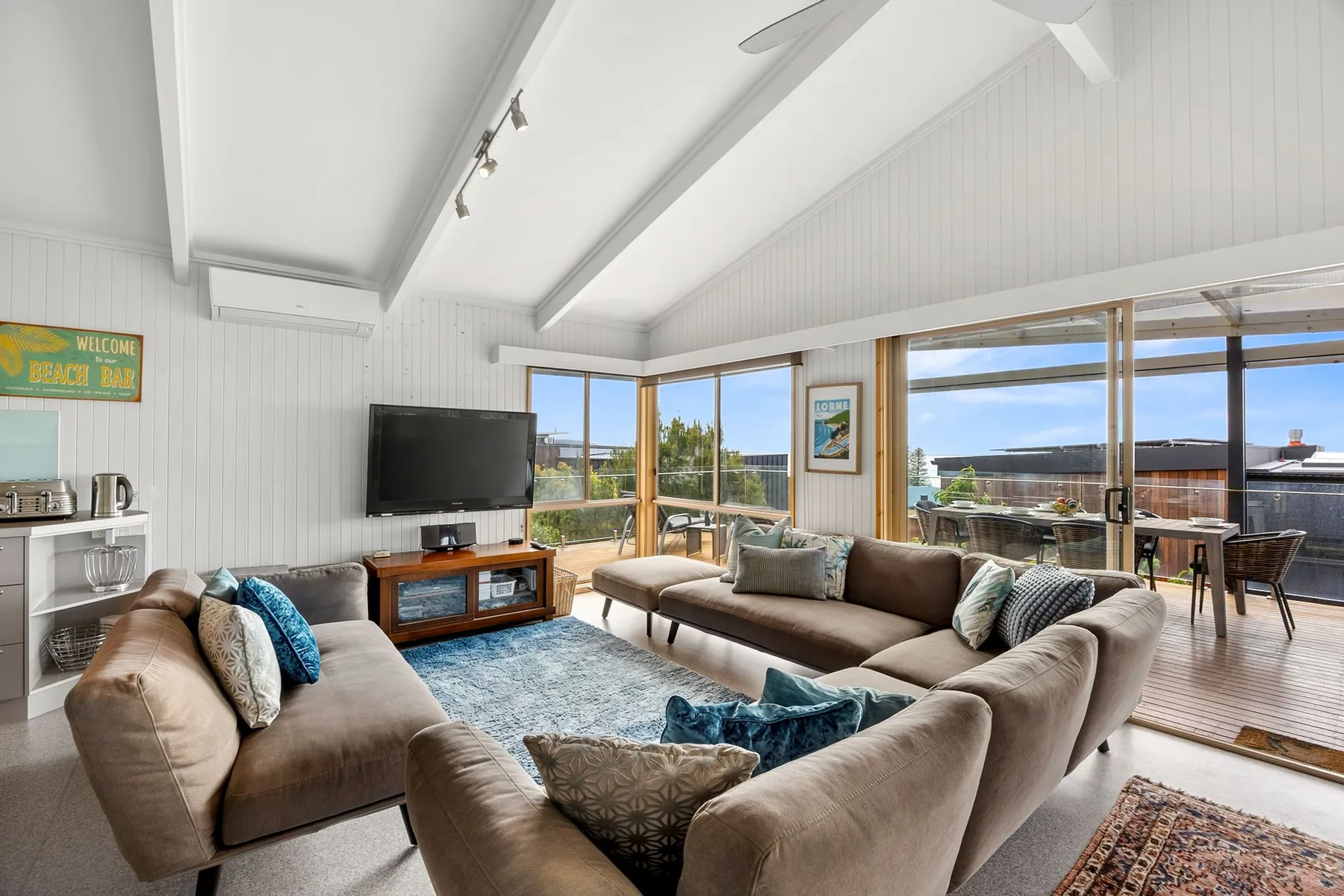 A bright living room with seating and large windows overlooking a deck.