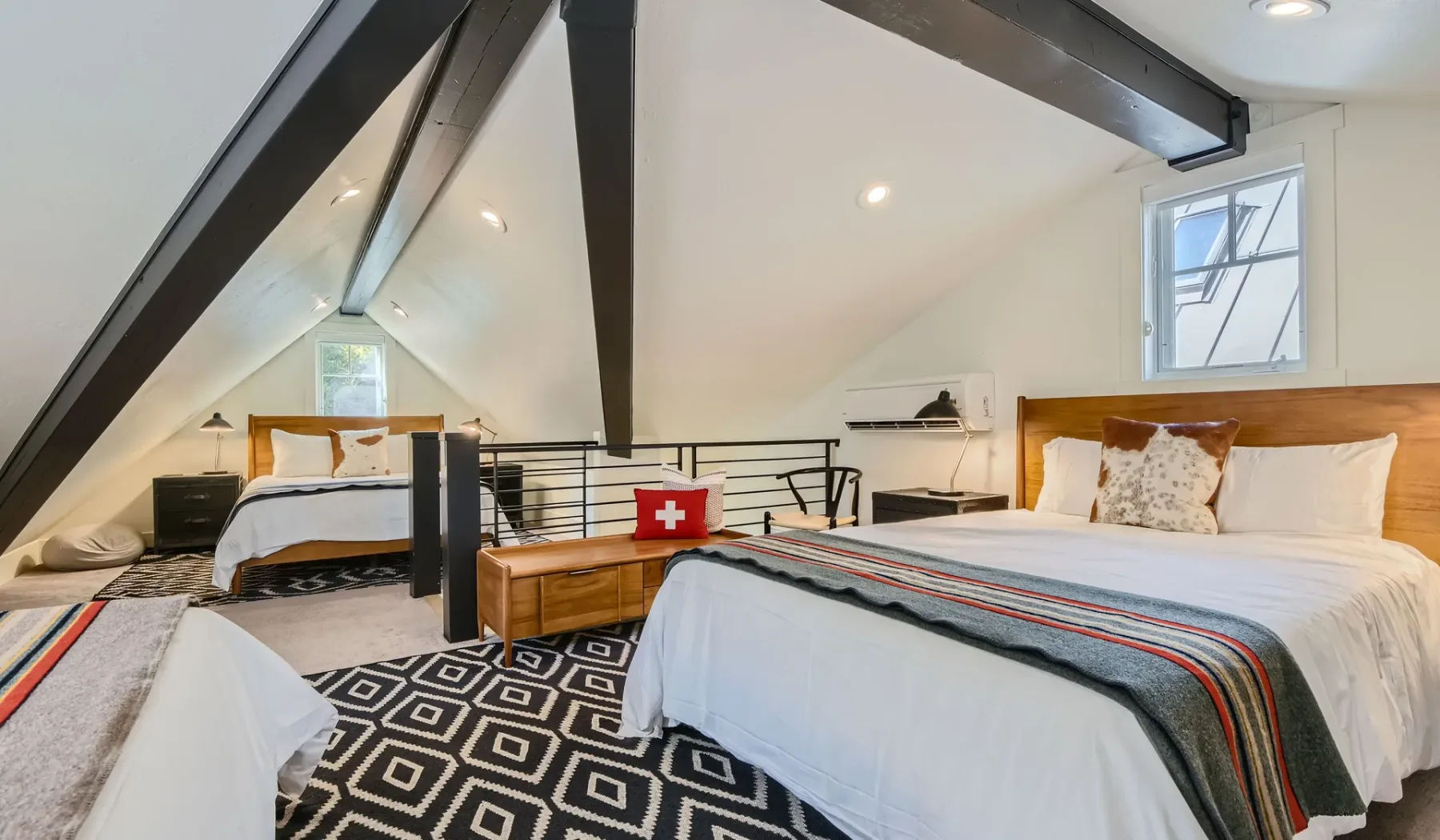 Un dormitorio abuhardillado luminoso con dos camas bajo techos inclinados.
