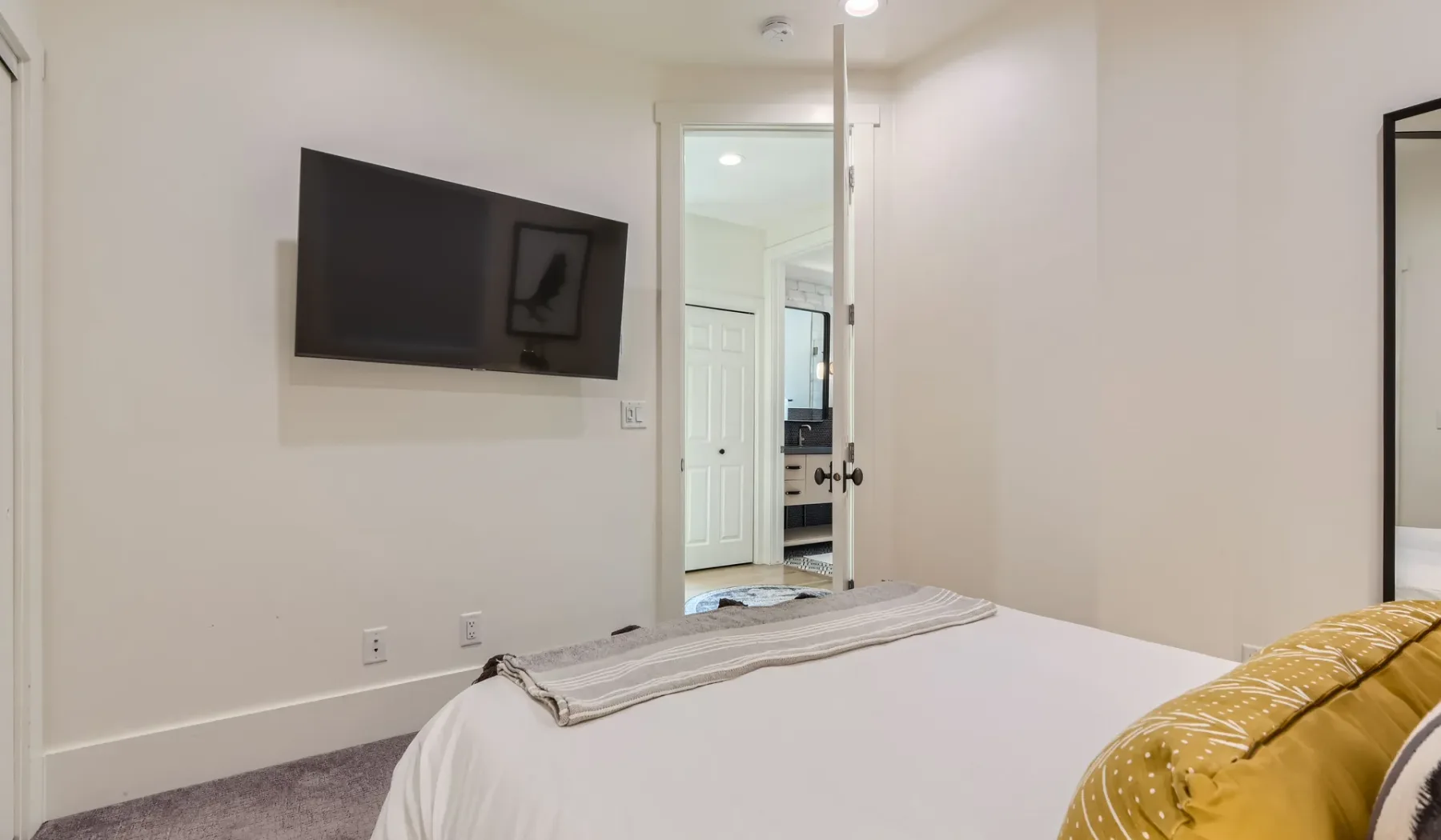 Un dormitorio con un televisor montado en la pared y una cama.