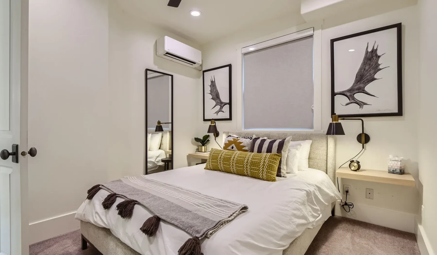 Un dormitorio con una cama bien arreglada, cuadros enmarcados y lámparas de pared.